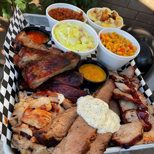 A Santa Maria BBQ platter with ribs, brisket, chicken, baked beans, potato salad, and corn.