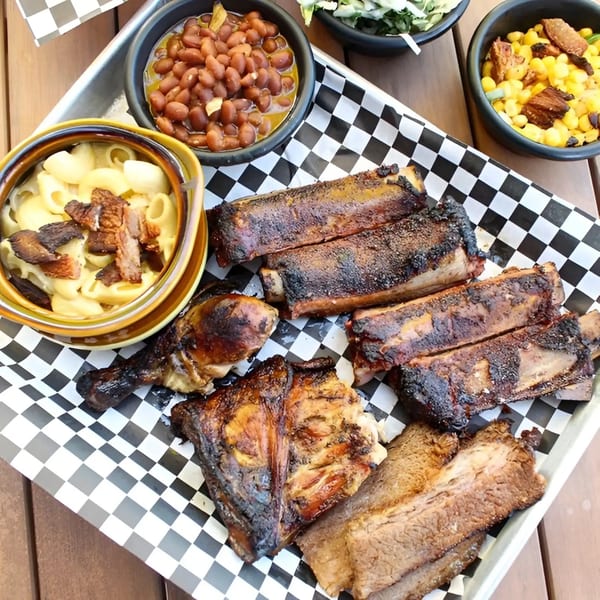 A Santa Maria BBQ platter with ribs, chicken, brisket, mac and cheese, baked beans, and corn.