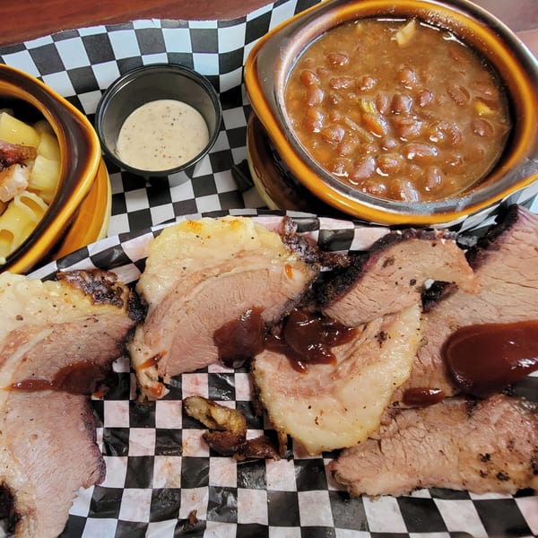 Platter of Santa Maria BBQ brisket with baked beans, macaroni and cheese, and dipping sauce.