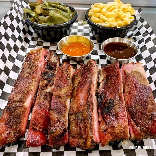 Santa Maria BBQ ribs with sides of collard greens, mac and cheese, and two dipping sauces.